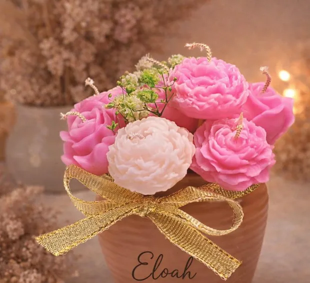 Velas decorativas con forma de rosas en una maceta de barro