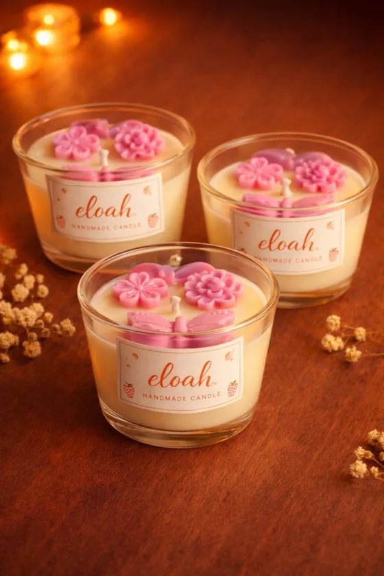 Tres velas en vaso con flores de cera rosadas encima